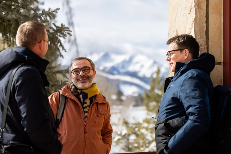 Three researchers talking outdoors with mountains behind at a Keystone Symposia meeting